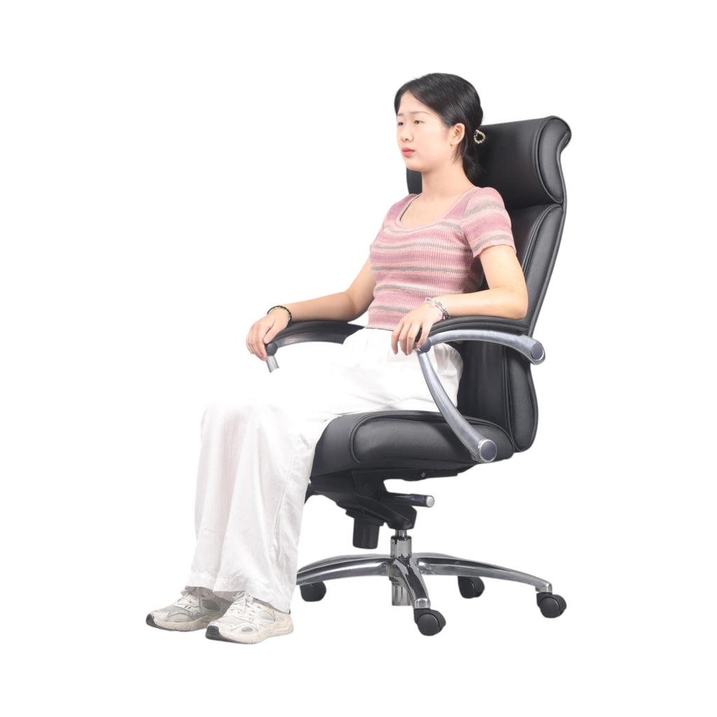 Xiaoyaozuo office chair: Black faux leather executive chair with high back, headrest, and chrome base with casters. Model seated.